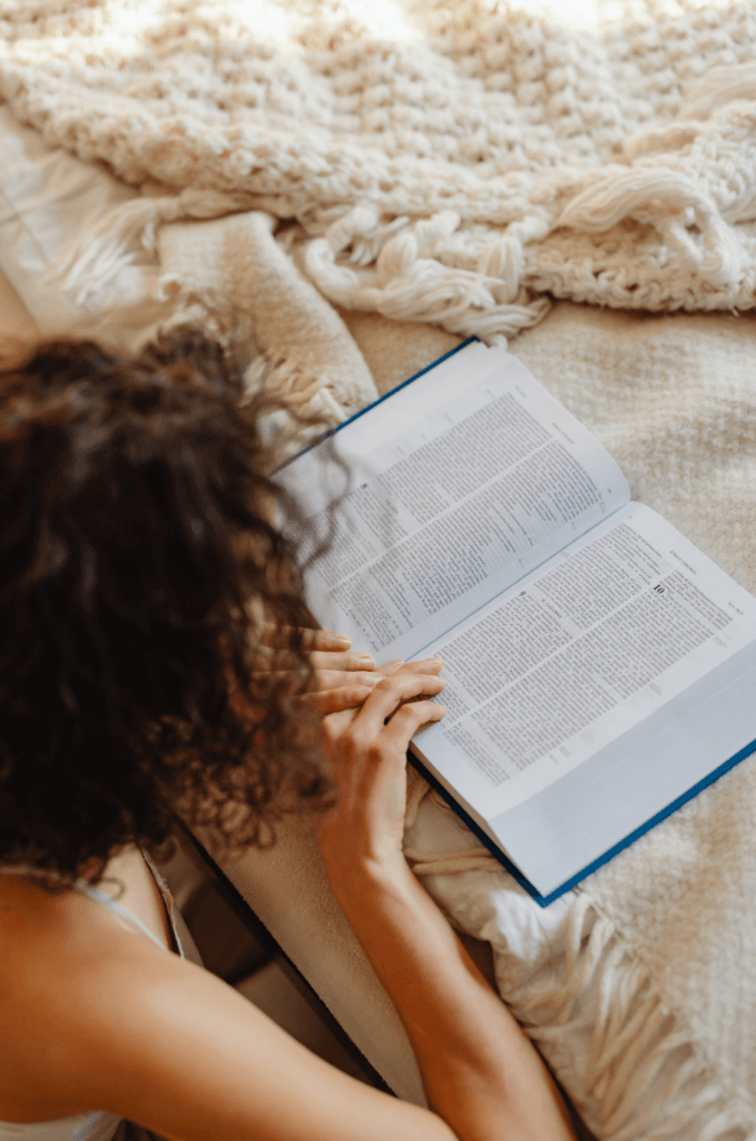 Mujer leyendo la Biblia envuelta en una manta, símbolo de elegir confiar en Dios